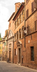 Fototapeta na wymiar Gloomy narrow medieval street in Italian city of Siena