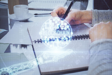 Cryptocurrency hologram over woman's hands writing background. Concept of blockchain. Multi exposure
