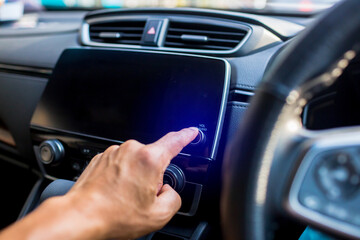 Selective focus to driver's finger touch on power button the smart monitor screen at the console in the car. The concept of smart car.