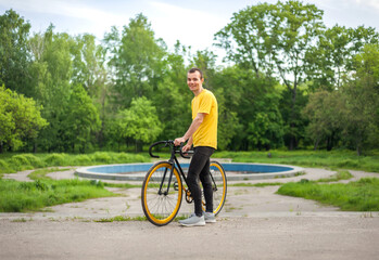 A young Man stopped to rest With his Bicycle in a public Park.