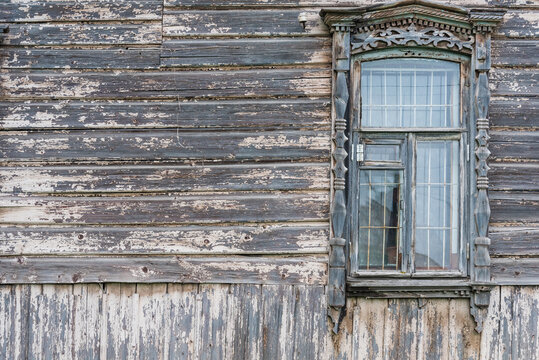 A very old house made of wood. Window with carved platbands. Background, texture. There is space for text.