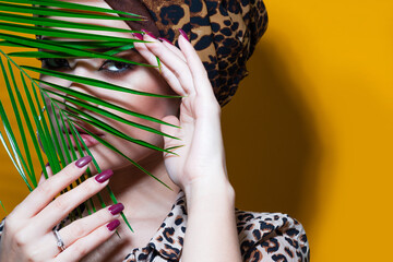 An attractive young woman in a stylish turban made of leopard print fabric on a yellow mango...