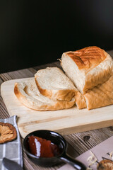 Fresh homemade loafs bread and sliced bread on cutting board with jam strawberry close up on wooden background.Healthy Diet.Prepared from a dough of flour and water, usually by baking.
