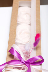 Marshmallows in craft paper packaging. Decorated with ribbons and dried flowers. Zephyr in the form of a rose. On white background.