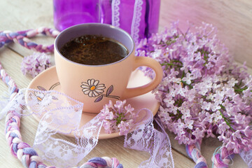 Violet cup of morning coffee or cappuccino and delicate pink, purple, lilac flowers. Mother's day concept. Cozy breakfast