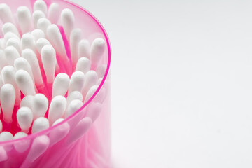 Cotton buds in a pink jar on a white background