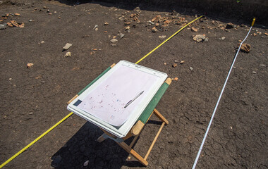 Archaeological drawing board sitting on a chair in front of a prehistoric feature