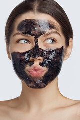Face masks are the perfect treatment to hydrate skin, remove excess oils and improve the appearance of pores. A girl with a black jelly-like mask with sequins on her face pouted her lips. 