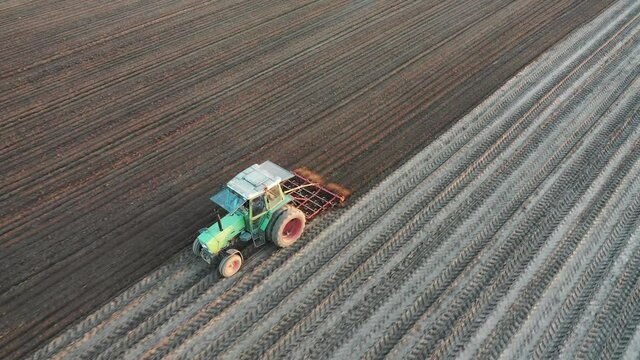 A farmer plowing his field with a tractor during spring, seen from above with a drone.