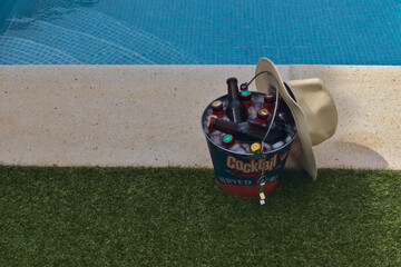 Quintos de cerveza en un cubo con hielo puesto en la coronación de una piscina