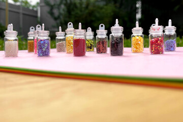 Colorful glitters for nail art and makeup in small glass jars isolated