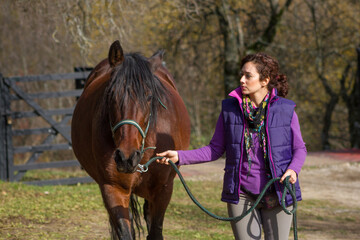 Woman taking her andalusian mare to graze in autumn.