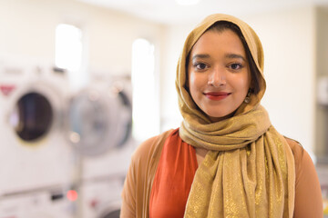 Face of young beautiful Indian Muslim businesswoman as owner of the laundromat