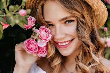 Close-up portrait of enchanting girl with shiny eyes posing with flower. Spectacular blonde woman...