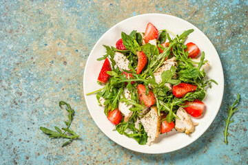 Green salad with chicken, strawberry and arugula.