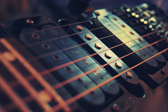 Close-up of an electric guitar bridge with humbuckers, single coil pickup, tremolo, strings and maple fretboard, noticable