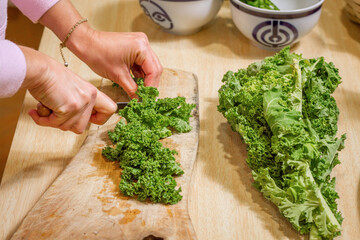 Female hands cutting a leaf of kale in the kitchen.