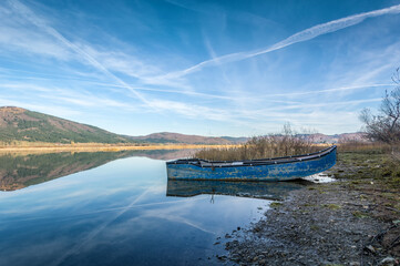 Small blue abandoned fishing boat. Lake Cerknica, one of the largest intermittent lakes in Europe. Low angle, wide shot