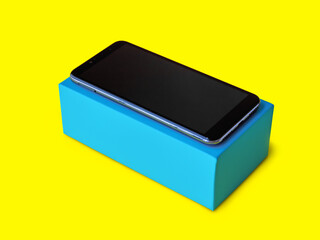 smartphone on a blue gift box on a yellow background