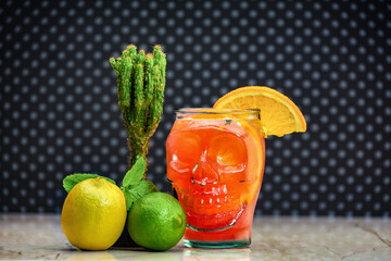 Fresh juice, alcohol, ice and an unusual mug in the shape of a head. Alcoholic halloween zombie cocktail consisting of absinthe, ru, cranberry and grapefruit juice in a glass skull-shaped.
