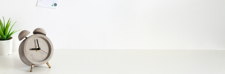 White desk with a concrete alarm clock. Blank wall copy space. Panorama