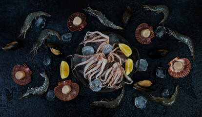 Fresh raw seafood with ice on a black background, top view