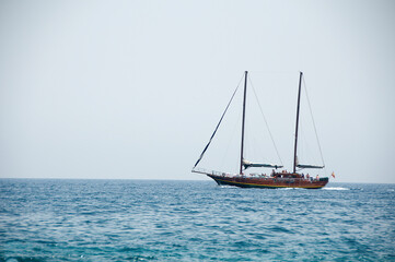 Fototapeta na wymiar un velero rojo con las velas bajadas navegando por el mar azul