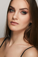 Fototapeta premium Beautiful face of young woman with clean fresh skin close up isolated on the grey background. Beauty portrait. Perfect fresh skin. Pure beauty model. Youth and skin care concept