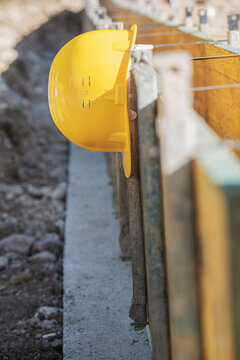 Yellow hardhat helmet hanging from supported wooden panels on a building site