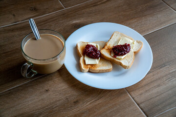 Cup of coffe with milk and two slices of toasted sandwich Bread with Butter and Raspberry Jam a white plate. Healthy breakfast with coffee. Top view. Free space for text.