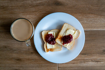 Cup of coffe with milk and two slices of toasted sandwich Bread with Butter and Raspberry. Breakfast with coffee. Side view. Free space for text.