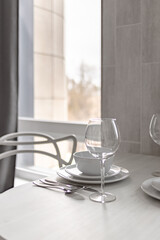 Table setting near the window - plates, wine glass, knife, fork and spoon 0070