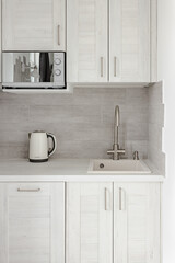 Fototapeta na wymiar Modern kitchen in a modern white house with microwave, kettle and sink 0066