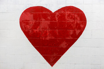 A big red heart is painted on a white wall. Street graffiti, street art expressing love