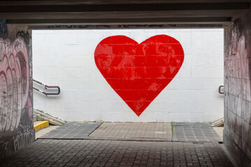 A big red heart is painted on a white wall. Street graffiti, street art expressing love
