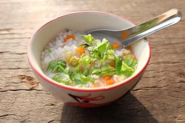 Rice porridge with sliced ​​Coriander, spring onions and carrots topping in bowl is tradition food breakfast in Thailand