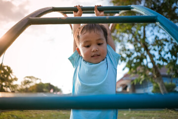 Fototapeta premium Cute little boy playing and hanging on ladder in kid playground