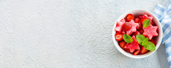 Summer salad with watermelon and strawberry on concrete background table, top view with copy space,...