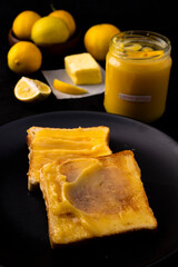 Lemon butter on two pieces of toast, lemons and a jar with a tag which is handwritten 