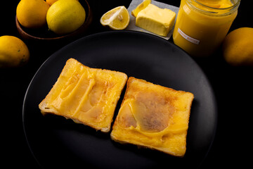 Lemon butter on two pieces of toast, lemons and a jar with a tag which is handwritten 