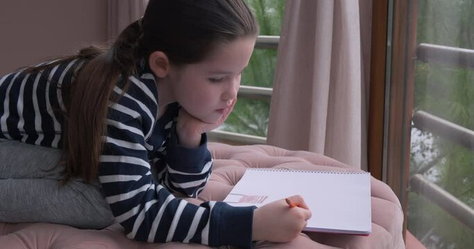 A little girl drawing with pencils at home