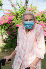 Elderly lady wearing mask, walking in garden