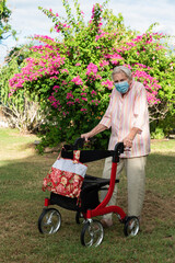 Old lady walking in garden wearing mask with walking aid