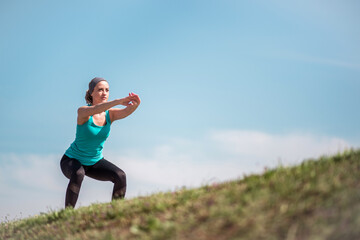 Young determined woman exercising squats outdoors