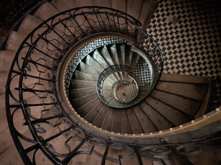 Vintage spiral staircase in an old European house. Top view, dark light.