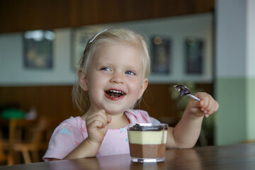 Candid portrait of a toddler girl eating chocolate cake. Happy childhood concept.