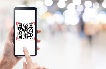 Hand using mobile smart phone scan Qr code on shopping mall background. Barcode reader, Qr code payment, Cashless technology, Digital money concept.