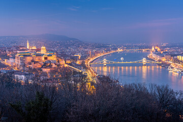 Budapest skyline with Buda castle and Szechenyi Chain Bridge reflect in Danube river during twilight