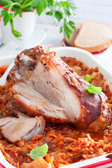 Baked pork shank with enamelled cabbage on a wooden table, selective focus