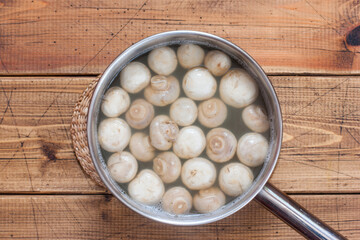 Korean-style salad dressing with champignons and carrots, step 2 - boiling the mushrooms, top view, selective focus